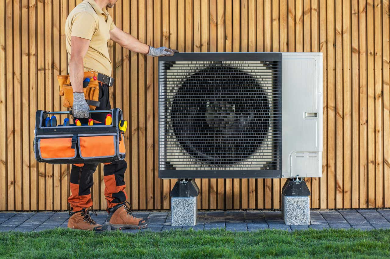HVAC technician holding toolbox while standing next to air conditioning unit