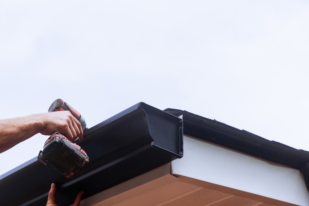 Gutter technician securing rain gutters on a roof